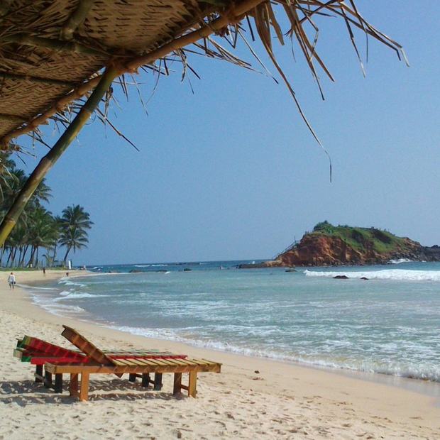 Mirissa beach with palms and Parrot Rock in the distance